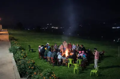 a group of people sitting around a fire at night at The Bowers Chalet Private Campfire & Lawn BBQ, WIFI, Breakfast Hill Top 360 degree view in Ooty
