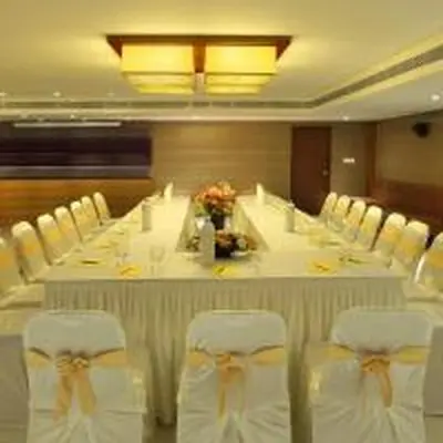 a long table with white chairs in a room at Jk Park Residency Perambra in Mennānyam