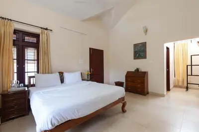 a bedroom with a large bed with white sheets at Crystal Homestay by StayVista - 4BR in Madikeri