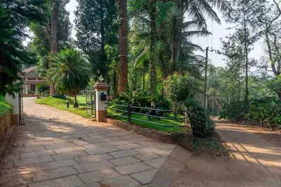 a path with a fence and trees and a house at Crystal Homestay by StayVista - 4BR in Madikeri
