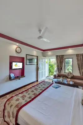 a large bedroom with a large bed and a couch at Club Mahindra Derby Green, Ooty in Ooty
