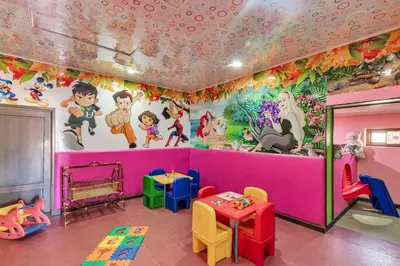 a room with a pink wall with cartoons on the wall at Club Mahindra Derby Green, Ooty in Ooty