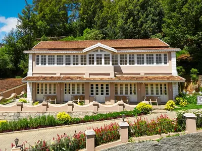 a large house with a garden in front of it at Club Mahindra Derby Green, Ooty in Ooty