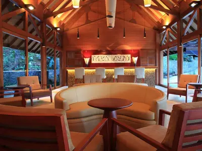a lobby of a resort with tables and chairs at The Tamara Coorg in Kakkabe