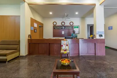 a lobby with a waiting area with a woman at a counter at KSTDC Hotel Mayura Biligiri, BR Hills in Honganūr