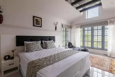 a bedroom with a large bed and windows at StayVista at Aashirwaad Villa in Coonoor
