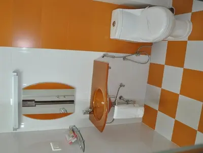 a bathroom with a toilet with an orange and white wall at Astoria Residency in Ooty