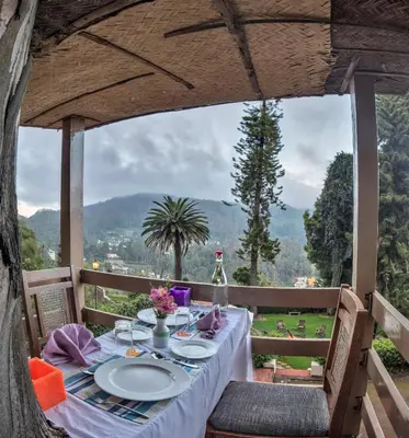 a dinner table with a view of the mountains at Club Mahindra Danish Villa, Ooty in Ooty