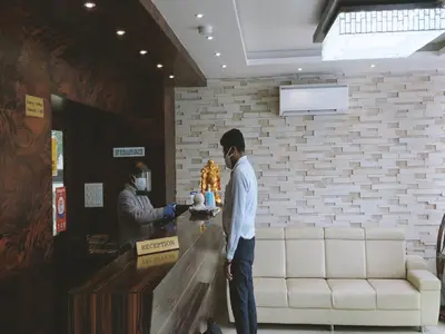 a man standing in a lobby with a counter with a man getting a cake at Heritage Inn in Mysore