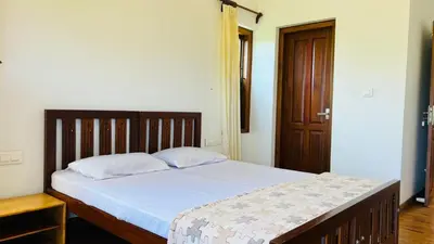 a bedroom with a bed and a wooden door at Pristine Hills in Meppādi