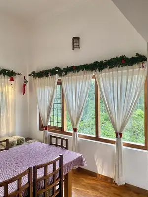 a dining room with a table with christmas garland at Pristine Hills in Meppādi