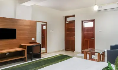 a bedroom with a bed and a desk and a television at Treebo Casino in Kozhikode