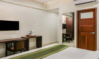a bedroom with a bed and a desk and a tv at Treebo Casino in Kozhikode