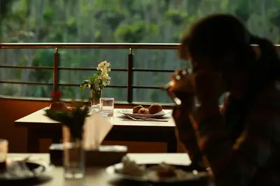 a woman sitting at a table with a plate of food at Dakshin Ghats in Tariyod