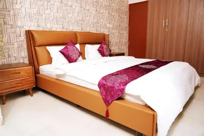 a bedroom with a large bed with white sheets and purple pillows at UNNATHI SUITES in Mysore