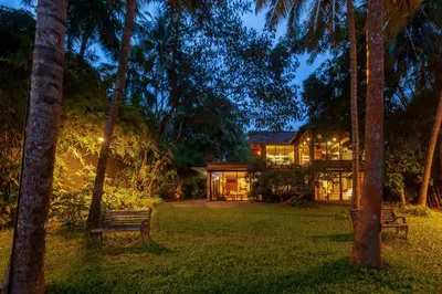 a house in the middle of a yard at night at StayVista at Toya Toya River View in Kozhikode
