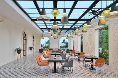 a lobby with tables and chairs and windows at Port Muziris, A Tribute Portfolio Hotel by Marriott, Kochi Airport in Nedumbassery