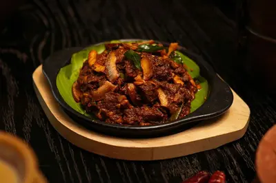 a green plate of food on a wooden table at Port Muziris, A Tribute Portfolio Hotel by Marriott, Kochi Airport in Nedumbassery