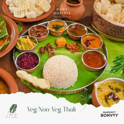 a table with a plate of rice and other foods at Port Muziris, A Tribute Portfolio Hotel by Marriott, Kochi Airport in Nedumbassery