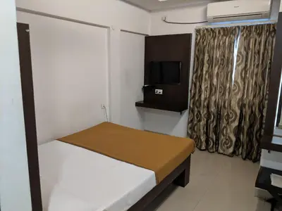 a small room with a bed and a tv at Aashraya in Mysore