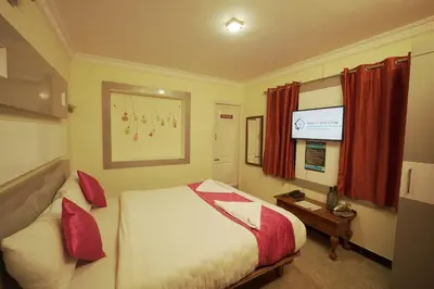 a hotel room with a bed and a television at Ganga's Sri Balaji Cottage in Ooty