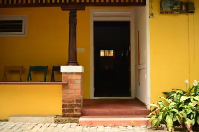 a yellow house with a black door and chairs at Design Ashram in Kozhikode