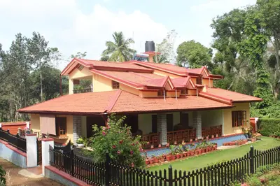 a house with a red roof and a black fence at Whistling Woods Farm Stay in Kushālnagar