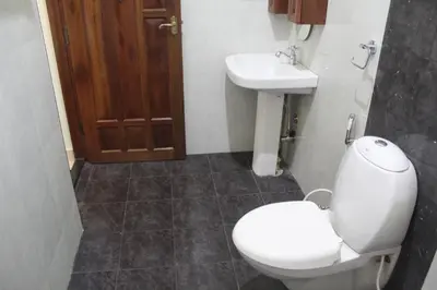 a bathroom with a toilet and a sink at Whistling Woods Farm Stay in Kushālnagar