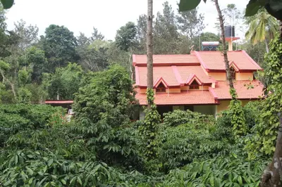 a house with a red roof in the jungle at Whistling Woods Farm Stay in Kushālnagar