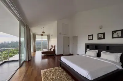 a bedroom with a large bed and a balcony at StayVista at The Lilly Ooty with Breakfast in Ooty