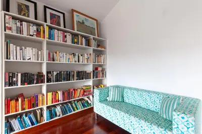 a book shelf filled with books next to a couch at StayVista at The Lilly Ooty with Breakfast in Ooty