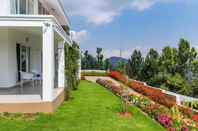 a house with a garden with flowers on the balcony at StayVista at The Lilly Ooty with Breakfast in Ooty