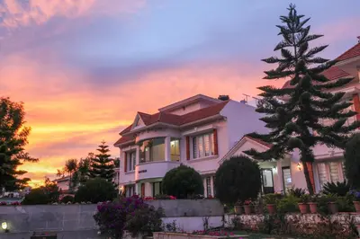 a house with a tree in front of a sunset at Twin Tree in Kotagiri