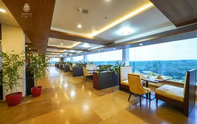a restaurant with plants and tables and chairs at KPM TRIPENTA HOTEL in Kozhikode