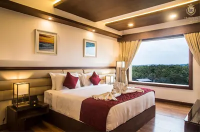 a bedroom with a bed and a large window at KPM TRIPENTA HOTEL in Kozhikode