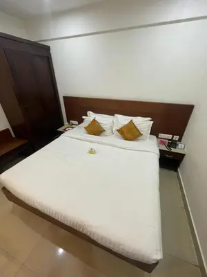 a bedroom with a large white bed with two pillows at Kallada Sangeetha Hotels in Trichūr