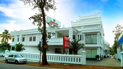 a white building with a car parked in front of it at Kallada hotels in Trichūr