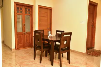 a dining room with a wooden table and chairs at Elegant Serviced Apartment in Mysore