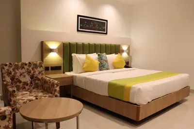 a hotel room with a bed and a chair at Hotel Park Residency Thrissur in Trichūr