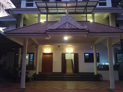 a house with a front porch with a brown door at Ocean Stay in Nedumbassery