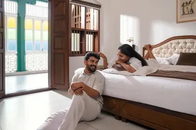 a man and a woman sitting on a bed at Villa De 1945 in Mahe