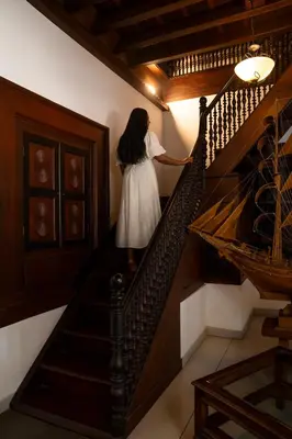 a woman in a white dress walking down the stairs at Villa De 1945 in Mahe