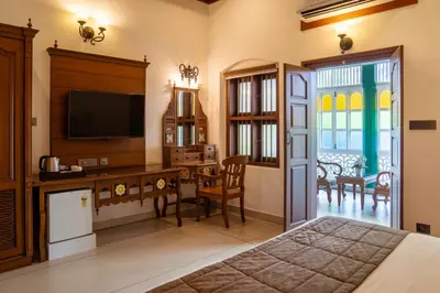 a bedroom with a bed and a desk with a television at Villa De 1945 in Mahe