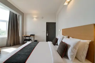 a hotel room with a large bed and a table at Super Townhouse Srm Kuppakonam Pudur in Coimbatore