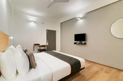 a white bedroom with a bed and a tv at Super Townhouse Srm Kuppakonam Pudur in Coimbatore