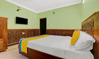 a bedroom with a large white bed with a television at Itsy Hotels Rain Forest, 1 km from Rose Garden in Ooty