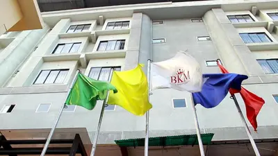 three different flags in front of a building at Hotel BKM International in Tellicherry