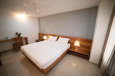a bedroom with a white bed with two pillows at Hotel BKM International in Tellicherry