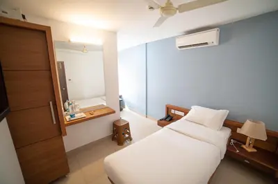 a bedroom with a white bed and a mirror at Hotel BKM International in Tellicherry