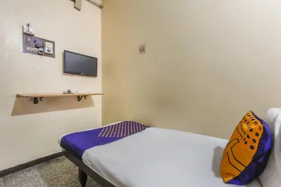 a bedroom with a bed and a tv on the wall at SPOT ON Thangam Lodge in Coimbatore